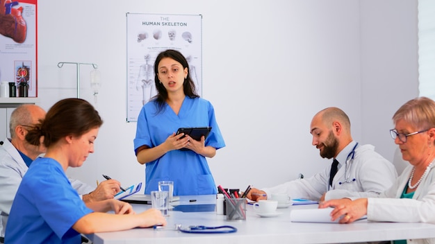 Doctors and nurses discussing a Medical Management Program in a hospital meeting room.